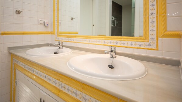A bathroom with two sinks, a mirror, and yellow decorative tiles. - Los Flamencos apto N56 (Manilva)