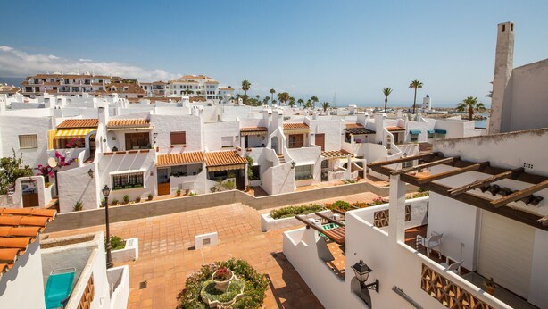 A coastal town with white buildings and terracotta roofs, featuring a courtyard with potted plants and a pool. - Los Flamencos apto N56 (Manilva)