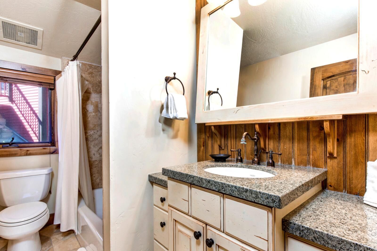 Een badkamer met toilet, wastafel, spiegel en douchegordijn.