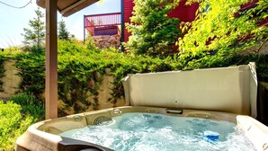 Un bain à remous doté d’un panneau de commande, entouré d’une végétation luxuriante et d’un mur en pierre.