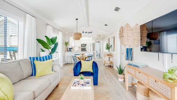 Ein modernes Wohnzimmer mit einer Couch, einem Sessel, einem Couchtisch und einem Fernseher auf einer Holzkommode.