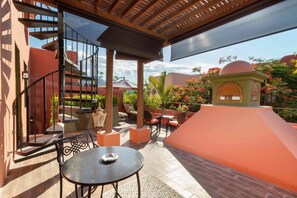 A covered outdoor patio with a spiral staircase, outdoor seating, and a small structure with a dome roof.