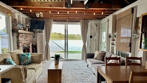 Een gezellige woonkamer met een met baksteen beklede open haard, een houten eettafel en een bank met bloemenkussens.