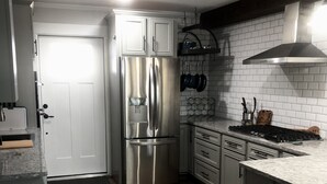A modern kitchen with a stainless steel refrigerator, white cabinets, and a wooden floor. - Cozy first floor in-town condo. (Blowing Rock)