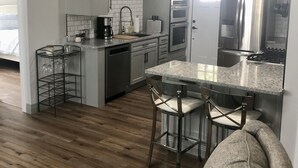 A modern kitchen with a central island, stainless steel appliances, and a bar area. - Cozy first floor in-town condo. (Blowing Rock)