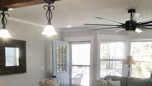A spacious living room with a large window, a ceiling fan, and a kitchen area with a marble countertop. - Cozy first floor in-town condo. (Blowing Rock)