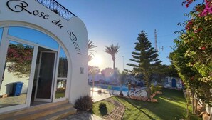 Entrada de un resort con vista despejada a una piscina y un césped bien cuidado.