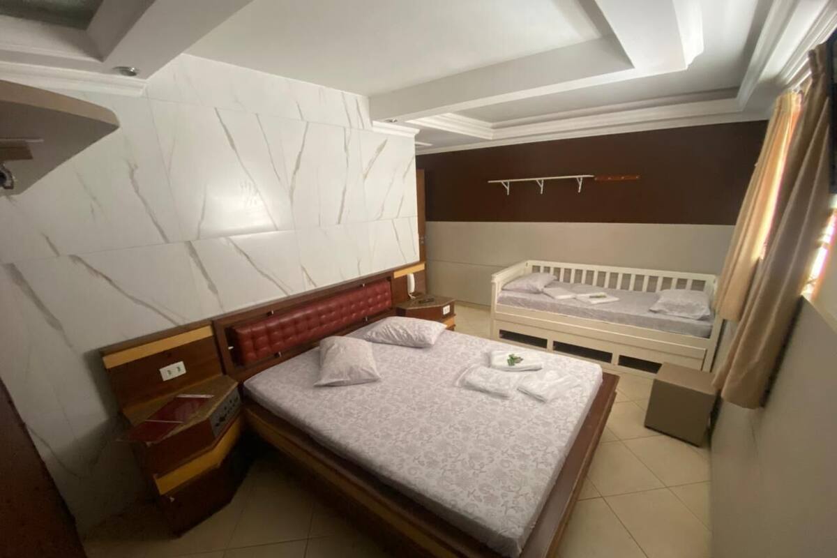 Un dormitorio con una cama grande, una cama más pequeña, una mesita de noche y un armario.