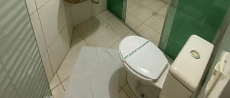 Un baño pequeño con inodoro, lavamanos y cabina de ducha de vidrio.
