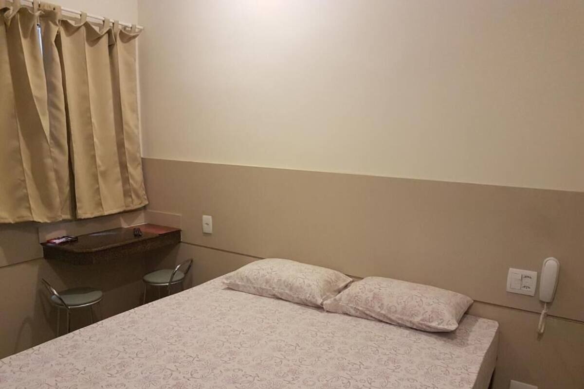 Habitación de hotel con una cama, un escritorio con sillas, un teléfono y una encimera de baño.