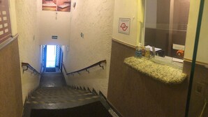 A narrow stairwell with a handrail, a sign indicating the exit, and a small shelf with toiletries. - Hotel Namorata Expo Inn (São Paulo)