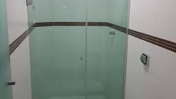 Un baño con ducha de vidrio, inodoro y lavamanos.