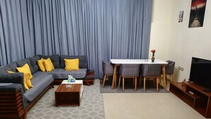 Ein Wohnzimmer mit Sofa, Couchtisch, Esstisch und Fernseher.