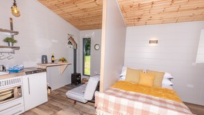 Habitación compacta con cama, kitchenette y un pequeño rincón de descanso.