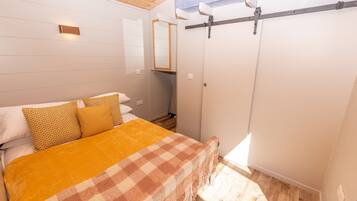 Une chambre à coucher avec un lit, une couverture à carreaux et une armoire.