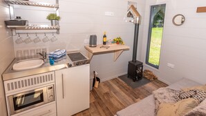 Cocina compacta con lavamanos, estufa, horno y una pequeña encimera. Hay una ventana que ofrece vistas al exterior.