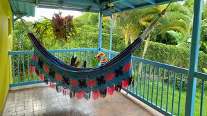 A hammock hanging on a balcony with a view of lush greenery. - Brugmansia Country Hotel (Montenegro)