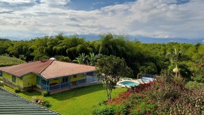 A house with a red roof and blue balcony, surrounded by lush greenery and a swimming pool. - Brugmansia Country Hotel (Montenegro)