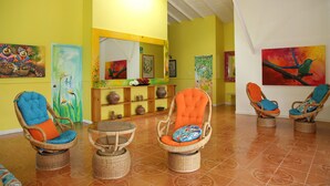A bright room with wicker chairs and a round table, yellow walls, and artwork on the walls. - Brugmansia Country Hotel (Montenegro)