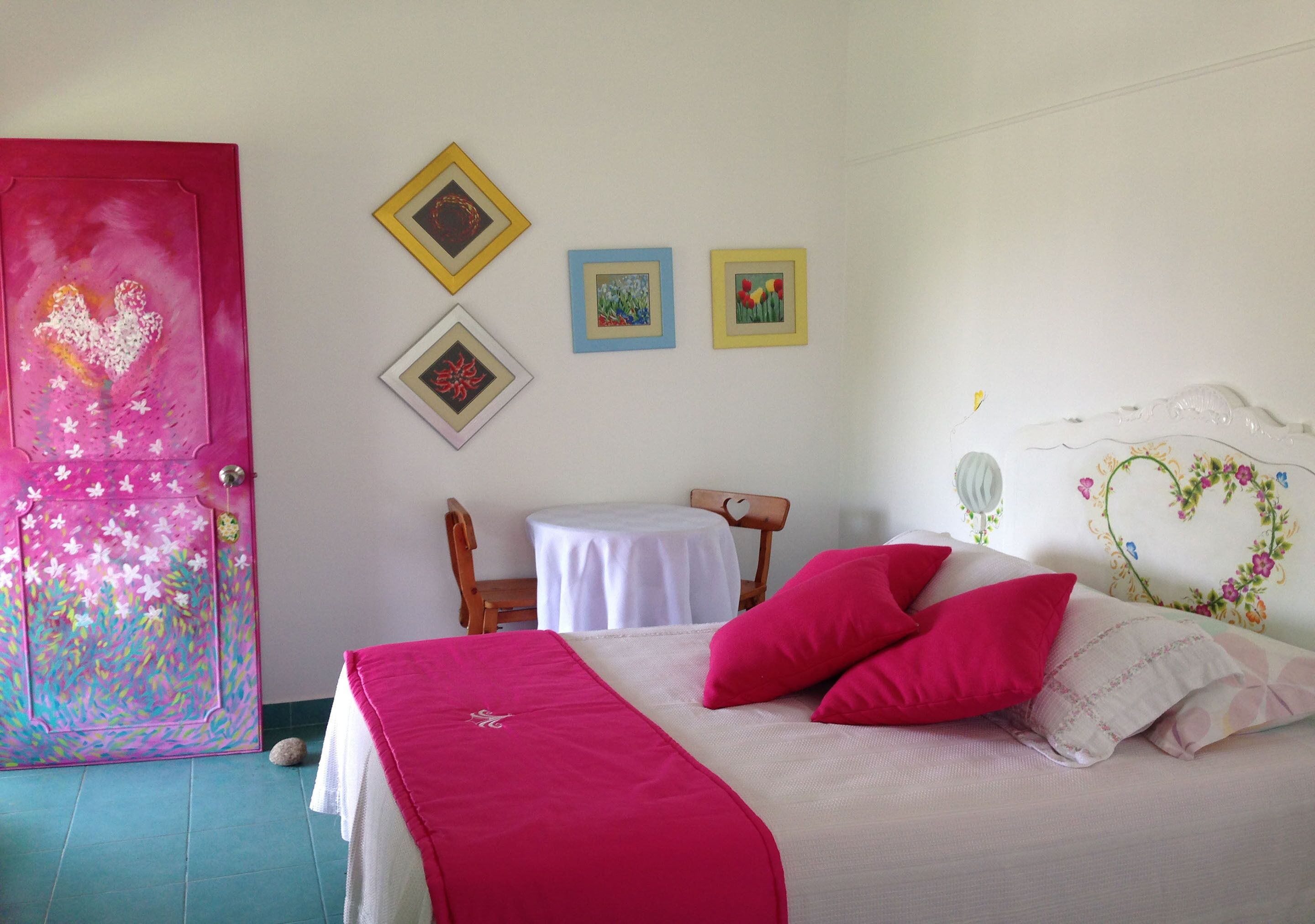 A bedroom with a bed, pillows, a small table, and chairs.