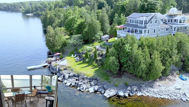 Una propiedad junto al lago con una casa grande, un muelle y una zona de patio.
