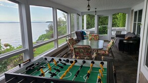 Una habitación con mesa de futbolín, una mesa de comedor con sillas y un sofá.