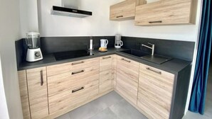 Een moderne keuken met houten kastjes, een zwart aanrecht, een ingebouwde kookplaat en een koffiezetapparaat.