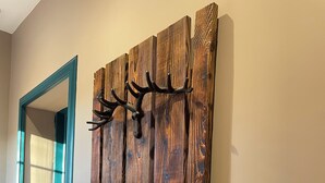 A hallway with a wooden wall art piece and a door with teal trim. - Tullochard House (Dunvegan)