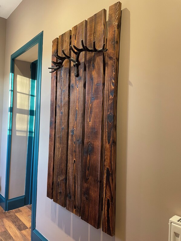 Un pasillo con un adorno de pared de madera y una puerta con detalles en color turquesa.