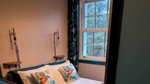 A bedroom with a bed, pillows, a window, and a wooden bench. - Tullochard House (Dunvegan)