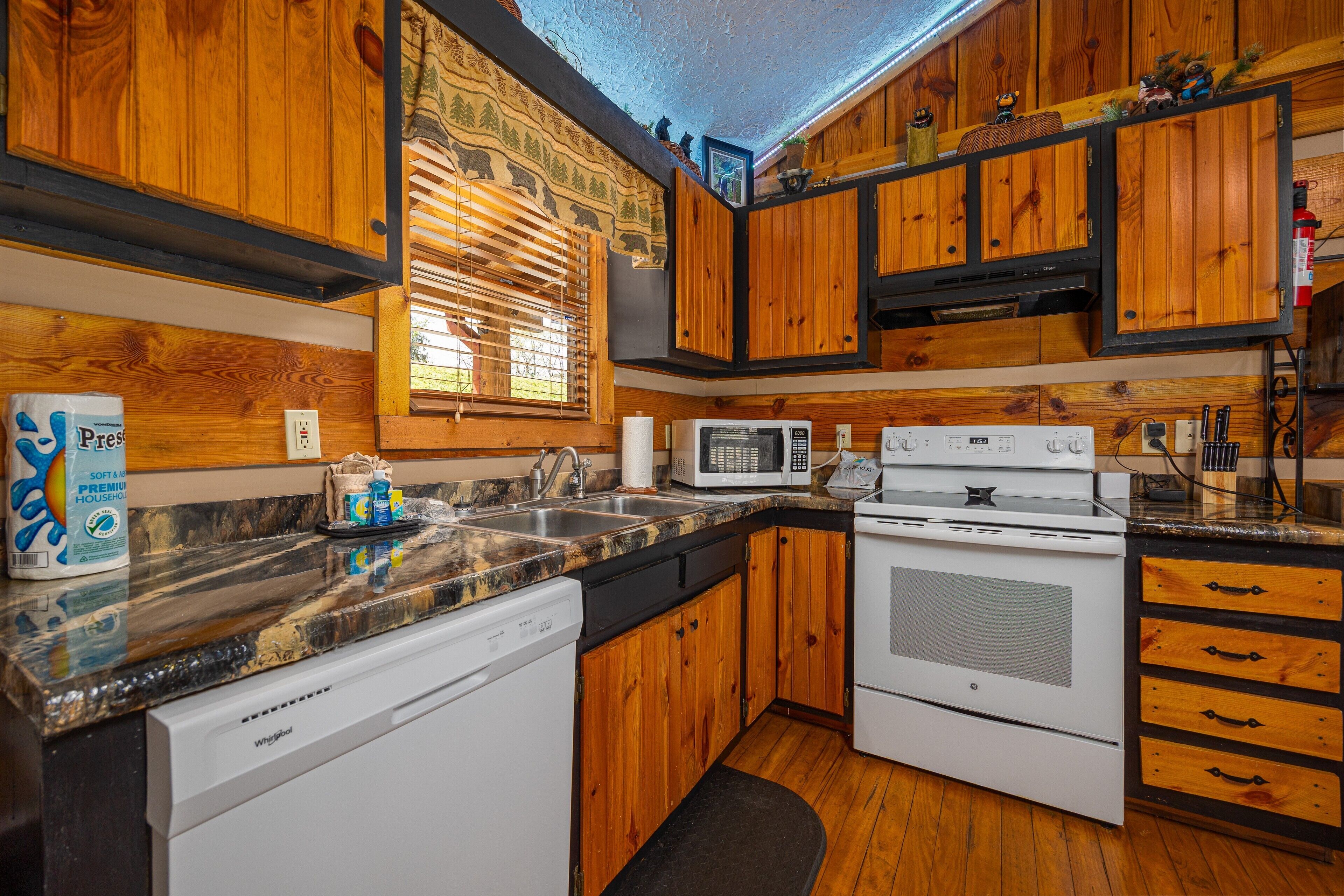 A kitchen with wooden cabinets, a microwave, a dishwasher, and a stove.