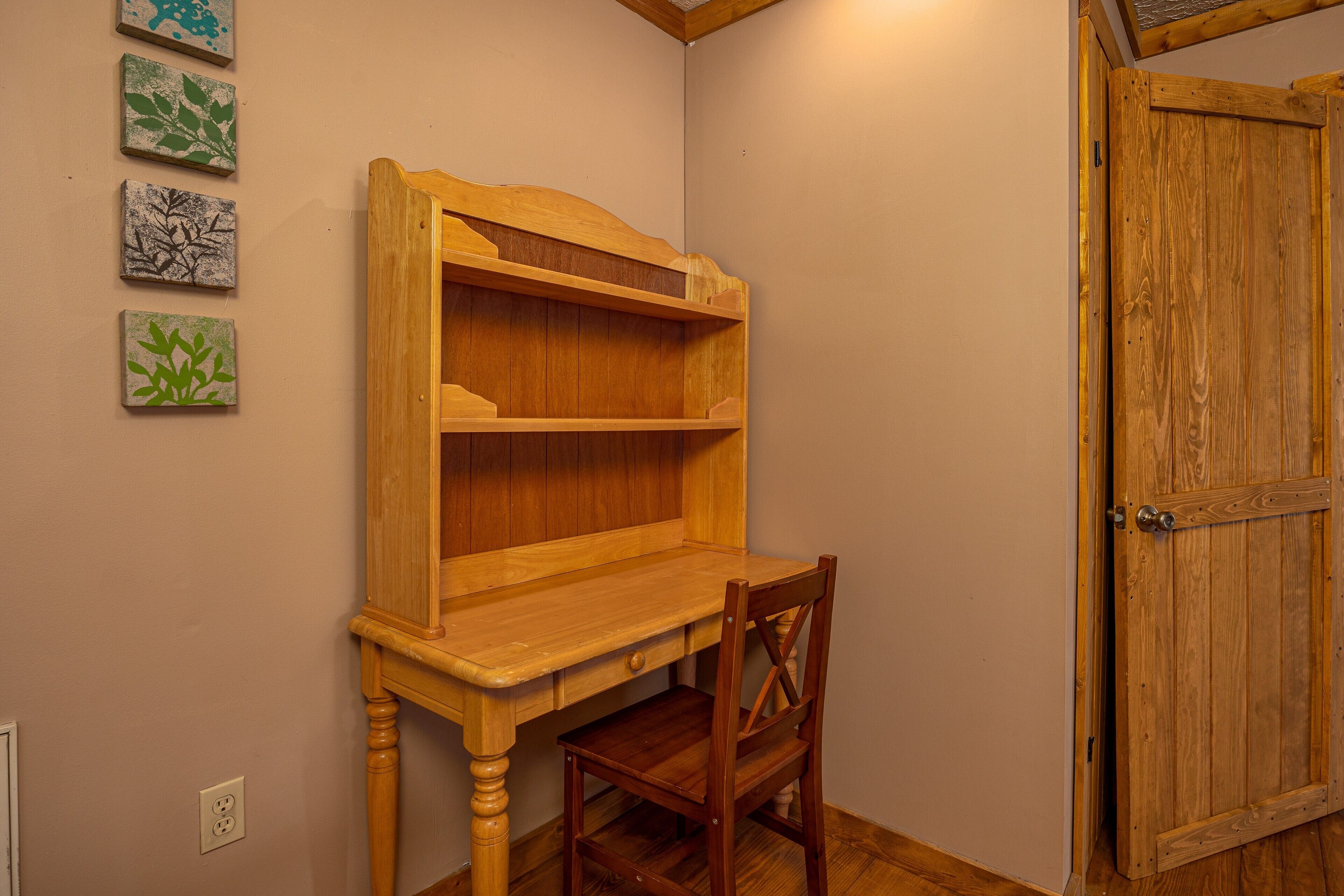 Ein Holztisch mit Stuhl, eine Holztür und vier an der Wand befestigte Kunstwerke.