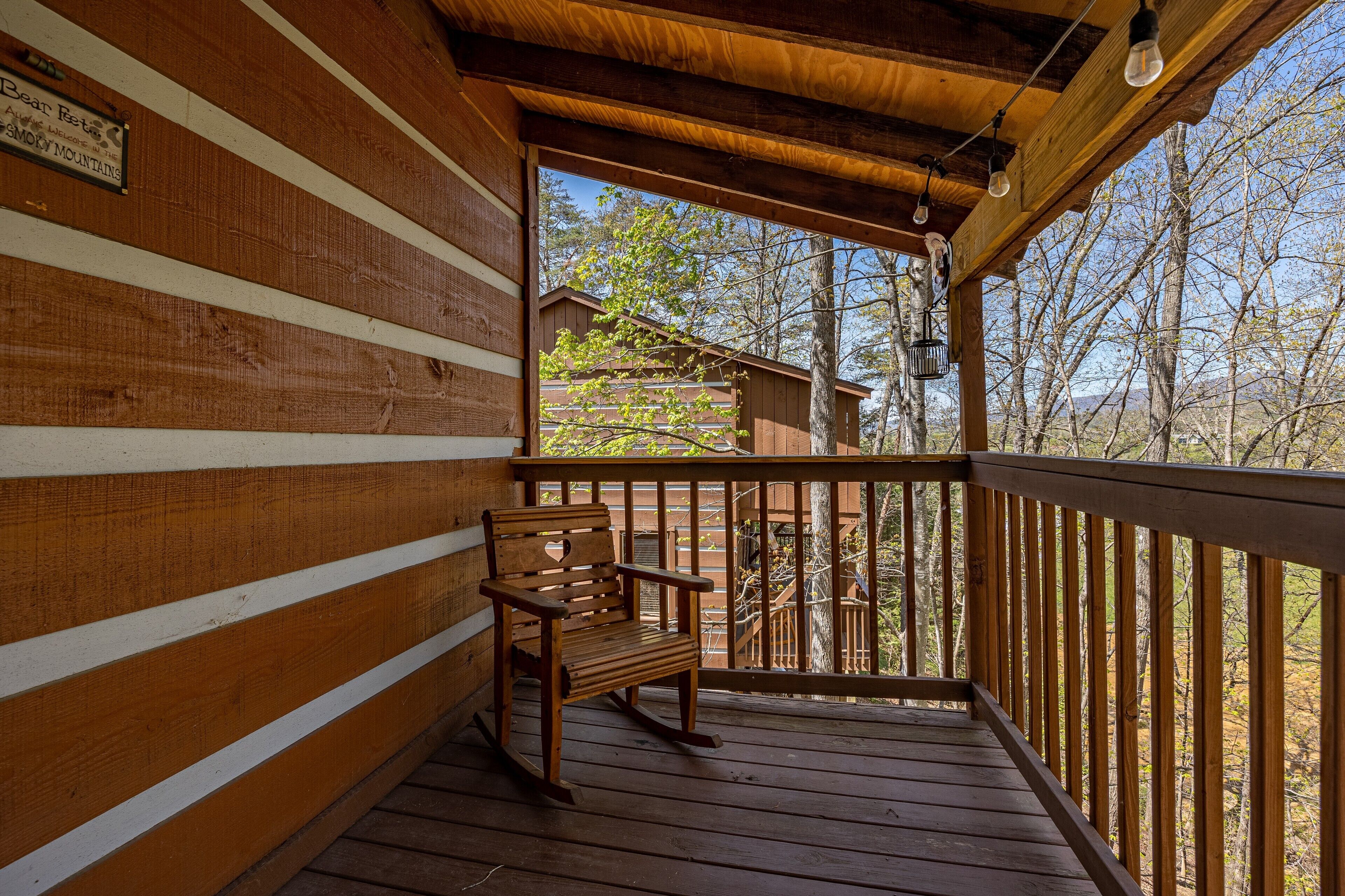 A wooden deck with a rocking chair and a wooden railing.