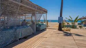 Un cabanon de plage avec une terrasse en bois, un espace salon et une vue sur l’océan.