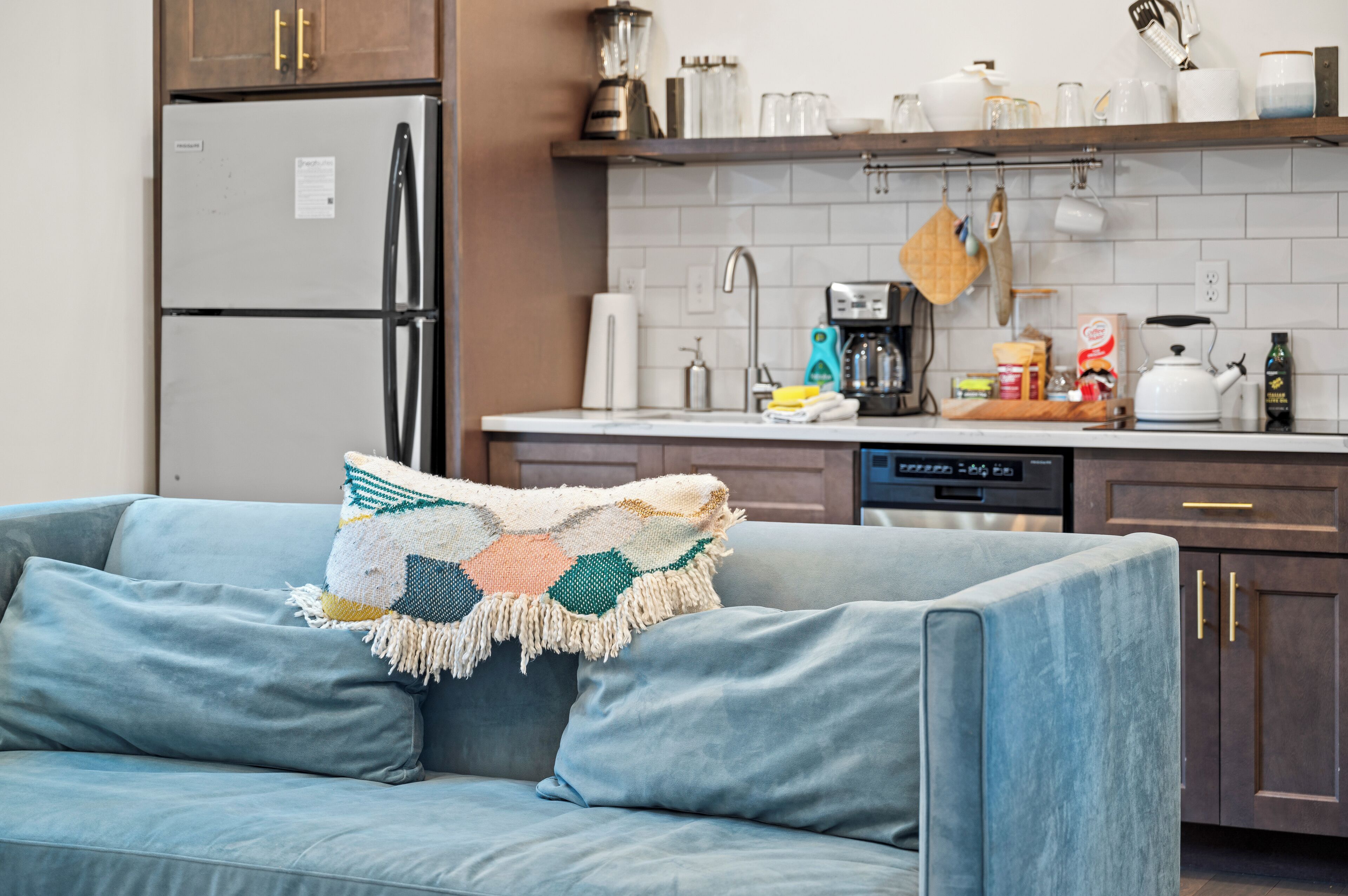 A modern kitchen with a grey refrigerator, a coffee maker, and a toaster on the counter.