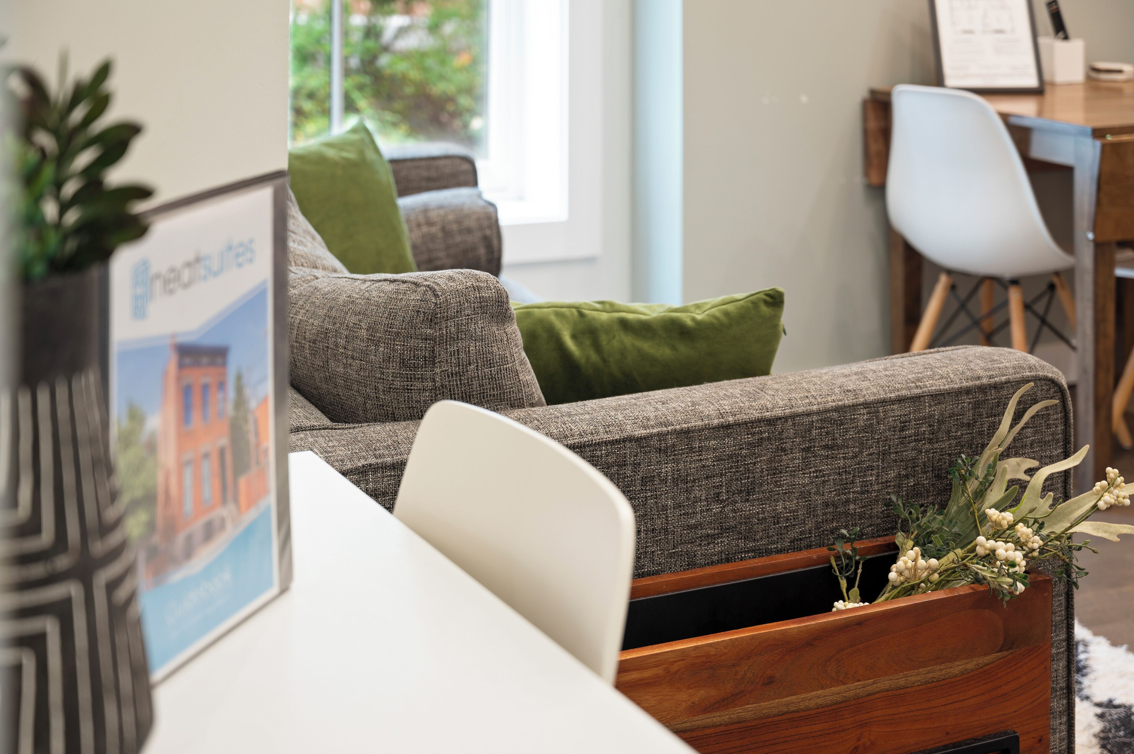 Ein modernes Wohnzimmer mit einem grauen Sofa, grünen Kissen und einem Holztisch.