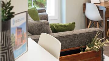 Ein modernes Wohnzimmer mit einem grauen Sofa, grünen Kissen und einem Holztisch.