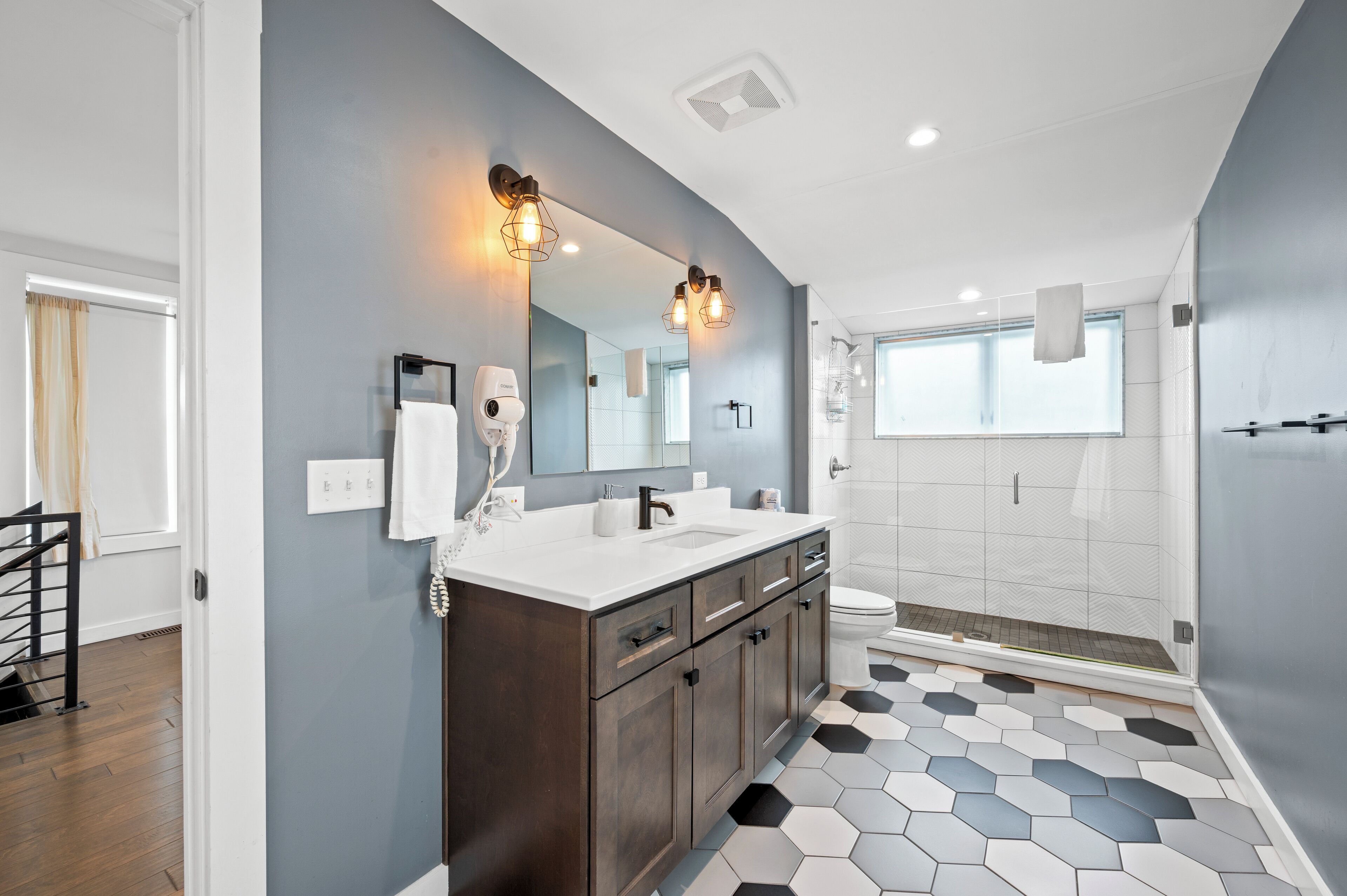 Une salle de bain moderne avec un grand miroir, deux lavabos et un espace douche.