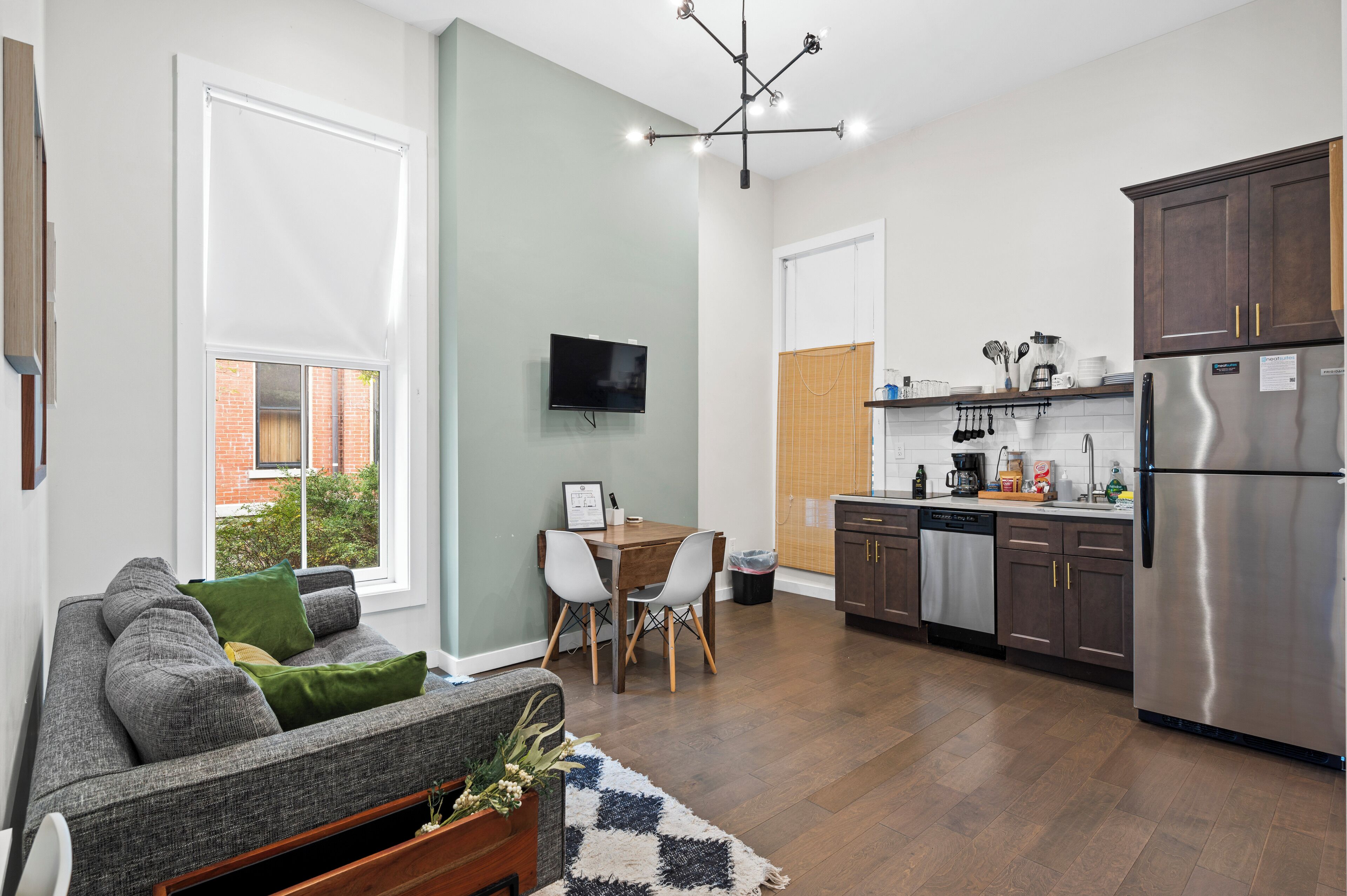 A modern kitchen with a stainless steel refrigerator, wooden cabinets, and a dining area with a table and chairs.