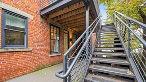 A brick building with a staircase leading to an upper level. - Baldwin Flats (Covington)