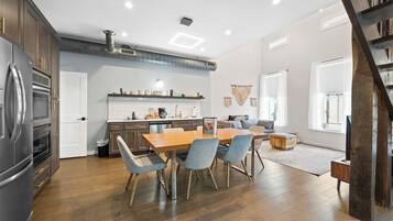 Una cocina amplia con armarios de madera, un refrigerador de acero inoxidable y un comedor con mesa y sillas de madera.