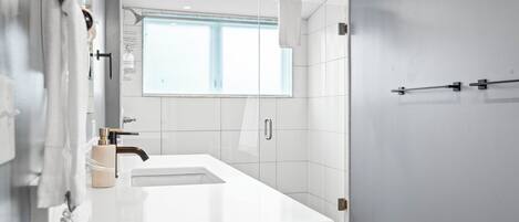Un baño moderno con un lavamanos amplio, ducha y ventana que proporciona luz natural.