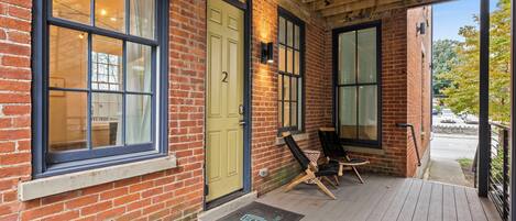 A brick building with large windows, a wooden deck, and a door with the number 2.