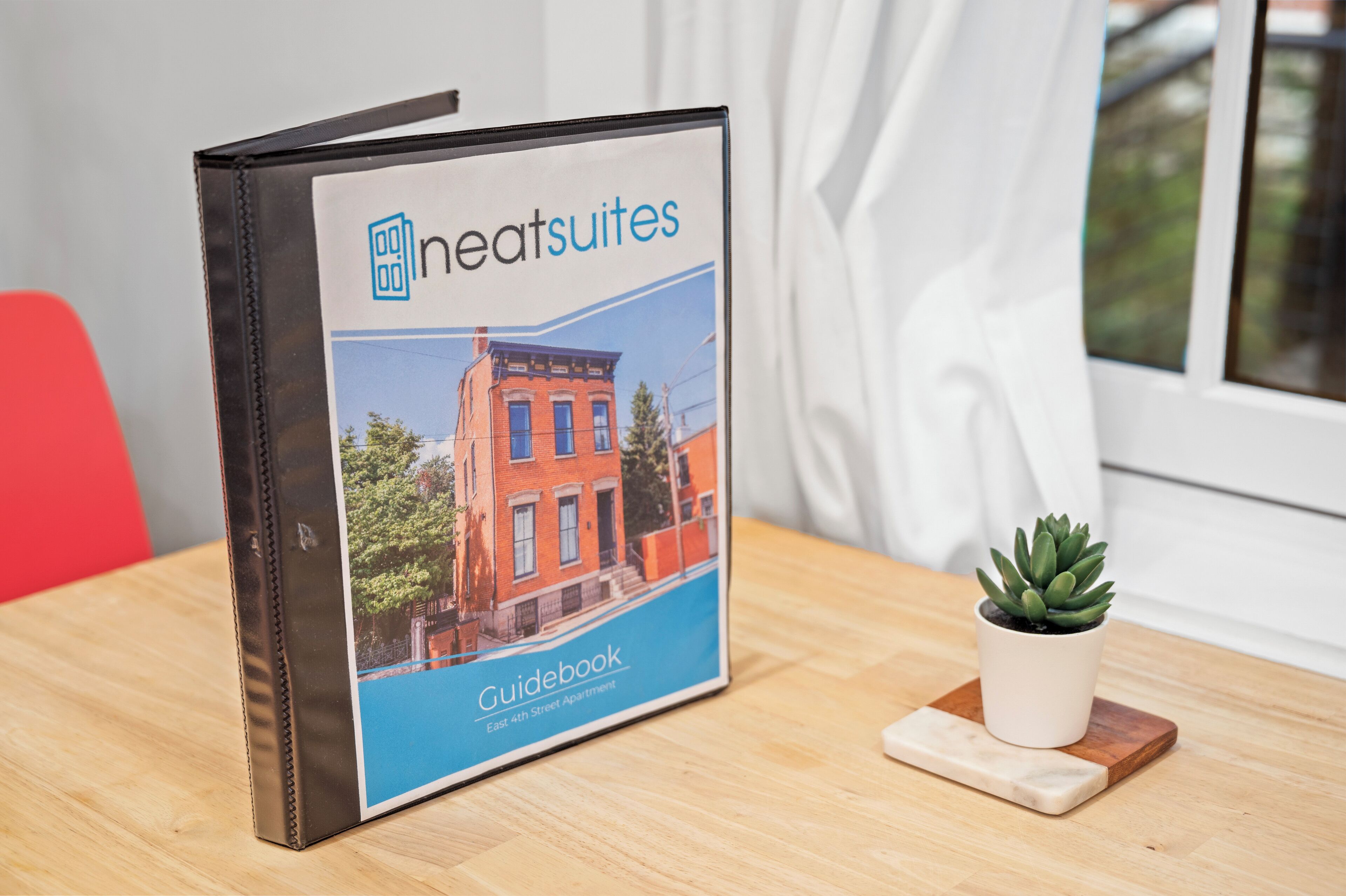 A guidebook titled "neatsuites" on a wooden table next to a small potted plant.