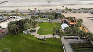 A coastal hotel with a central courtyard, palm trees, and a view of the beach.