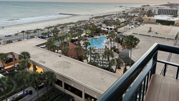 A resort with a pool, palm trees, and a beach view.