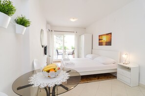 Ein modernes Schlafzimmer mit Glastisch, Obstschale, Bett, Nachttisch und Blick ins Freie.