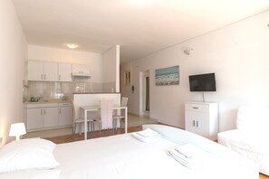 Habitación de hotel con cama, escritorio, silla, televisión y kitchenette.