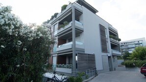 Un immeuble résidentiel moderne à plusieurs étages, doté de balcons, avec un vélo garé devant et une voiture stationnée à proximité.