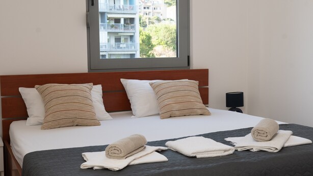 Une chambre d’hôtel avec un lit, des oreillers, une fenêtre et une table de chevet.